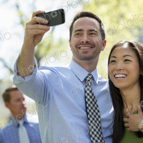 A small group of people. A couple with a smart phone, side by side. A man in the… A small group of people. A couple with a smart phone, side by side. A man in the…