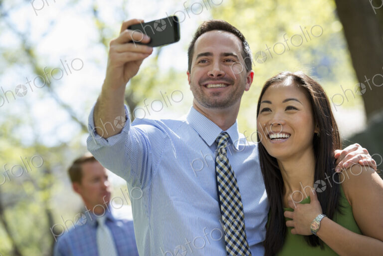 A small group of people. A couple with a smart phone, side by side. A man in the…
