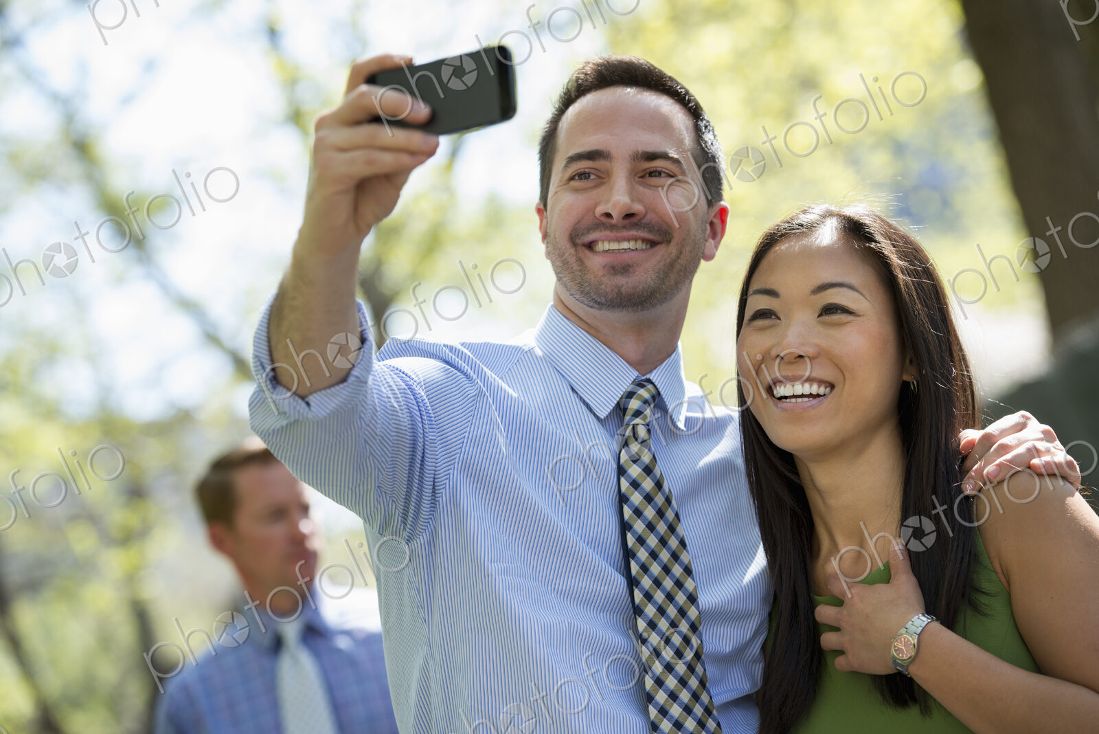 A small group of people. A couple with a smart phone, side by side. A man in the…