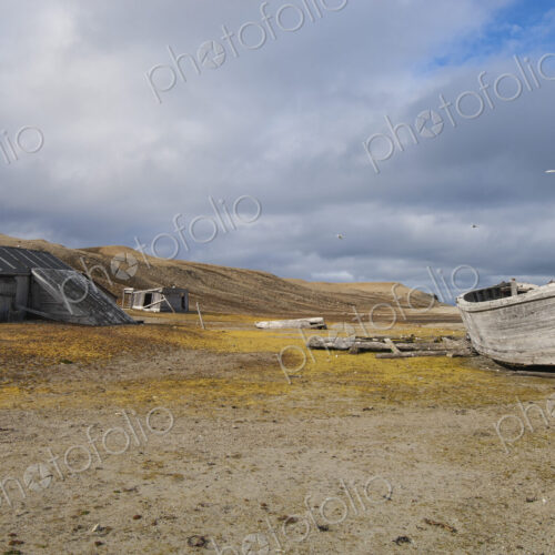 A small log cabin, a fishing hut with a beached boat.