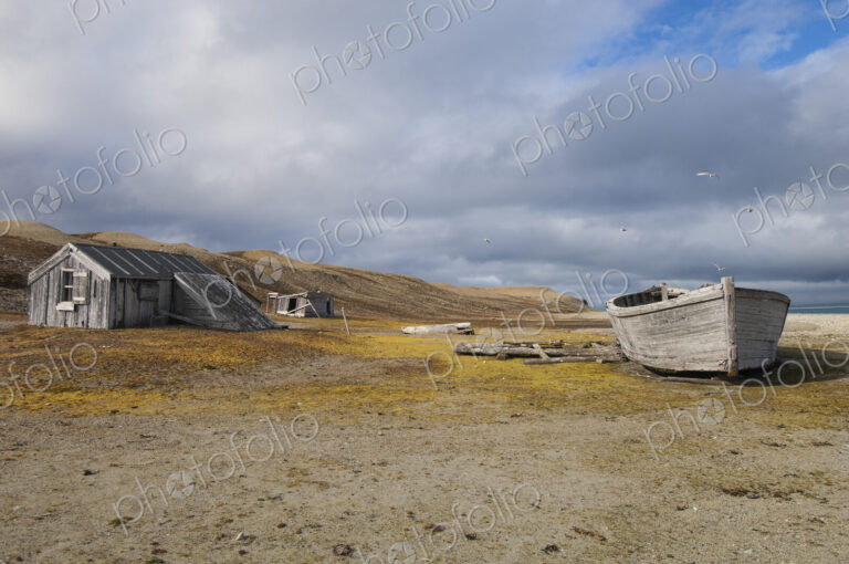 A small log cabin, a fishing hut with a beached boat.