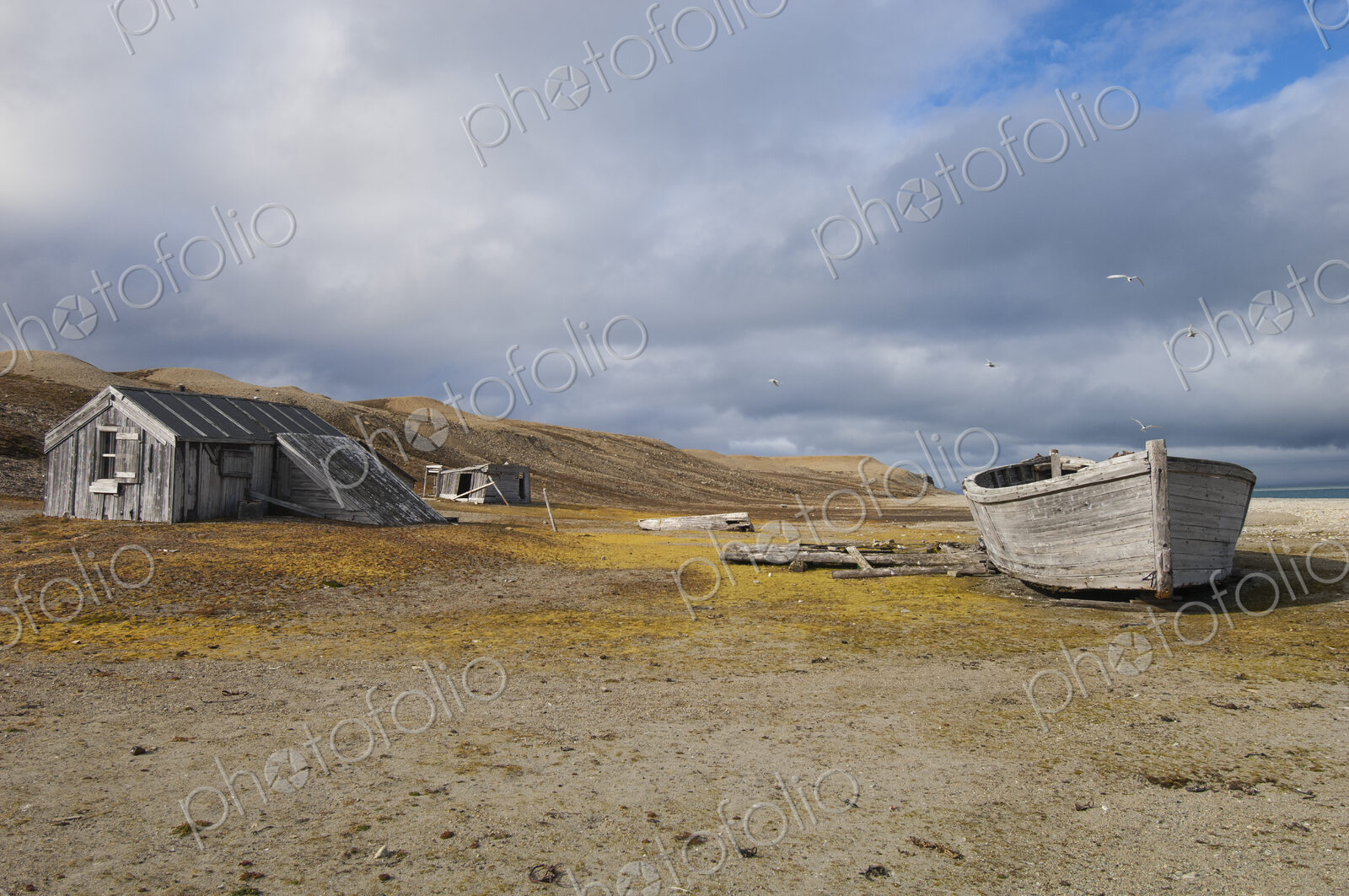 A small log cabin, a fishing hut with a beached boat.