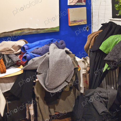 A small messy room with furniture covered in heaps of discarded clothes. A small messy room with furniture covered in heaps of discarded clothes.