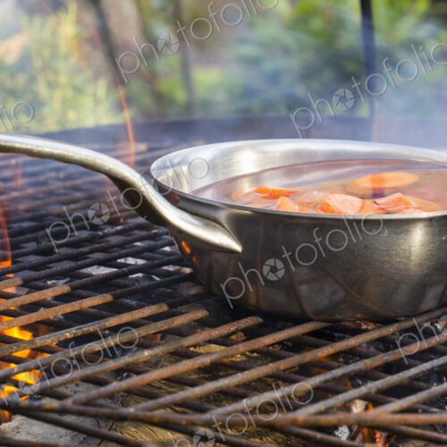 A small pan on a fire with blanched carrots. A small pan on a fire with blanched carrots.