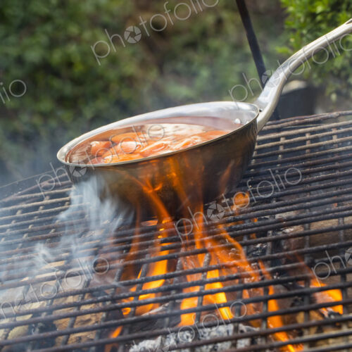 A small pan with sliced carrots over an open fire. A small pan with sliced carrots over an open fire.