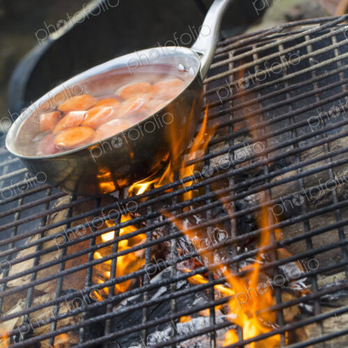 A small pan with sliced carrots over an open fire. A small pan with sliced carrots over an open fire.