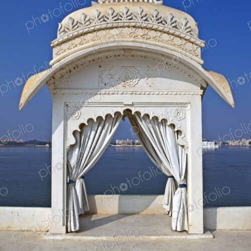 A small pavilion with a cupola, a scalloped carved stone arch with drapes drawn aside,… A small pavilion with a cupola, a scalloped carved stone arch with drapes drawn aside,…