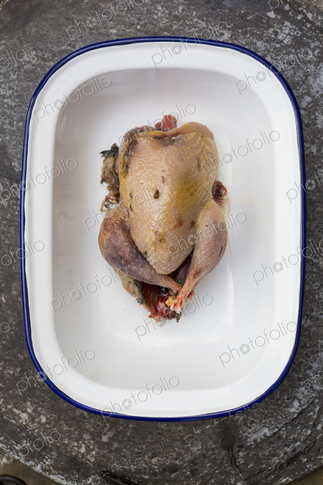 A small plucked game bird in a tin, ready for rcooking.