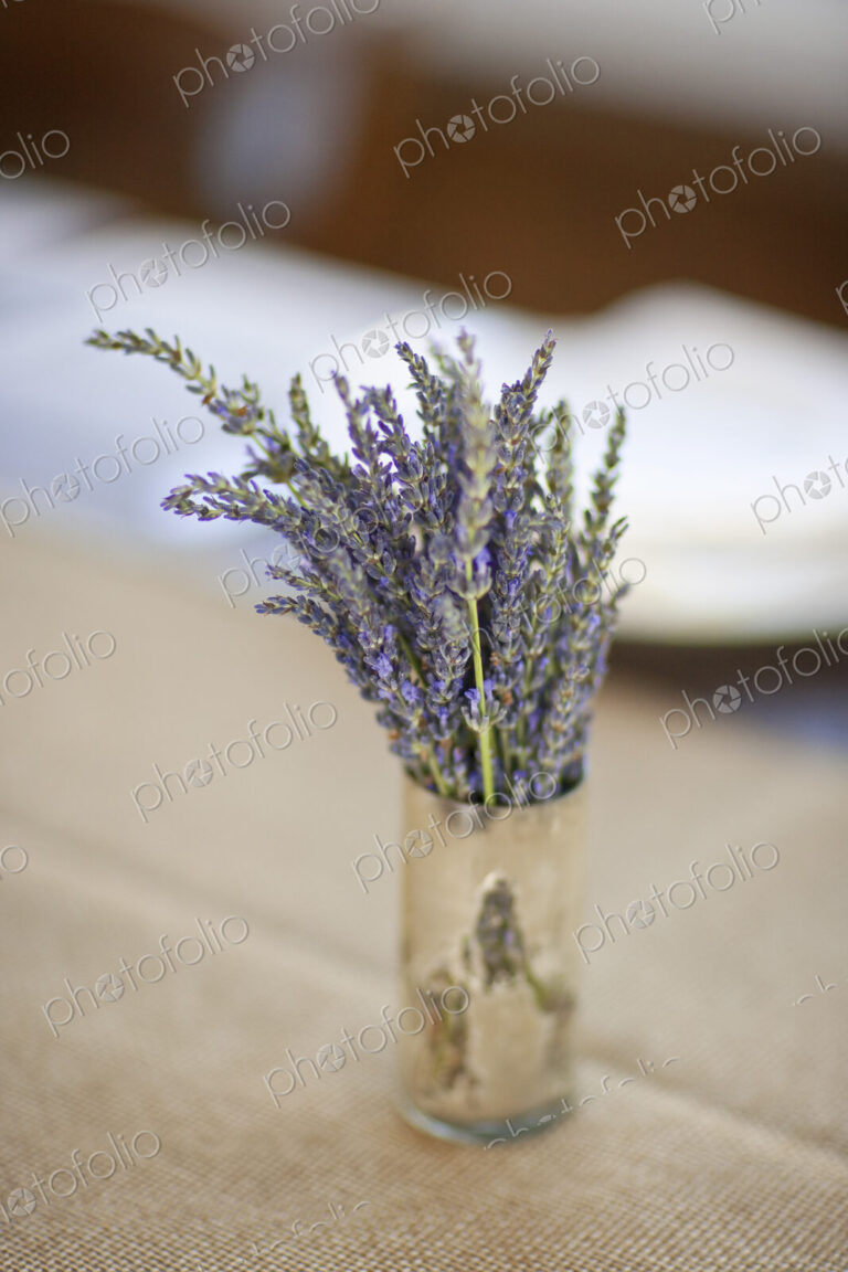 A small pot with fresh lavender flowers on a table top.