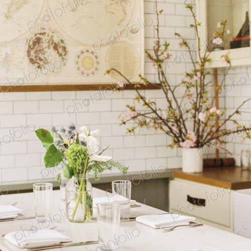A small table with four place settings and flowers in a jar. A small table with four place settings and flowers in a jar.