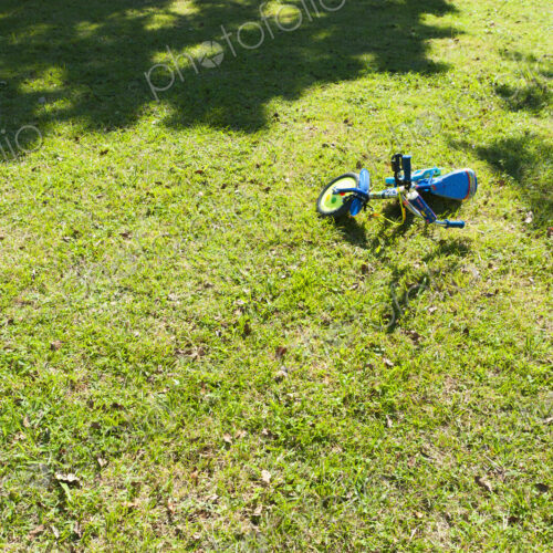 A small two wheeled decorated child's bicycle on its side on the grass. A small two wheeled decorated child's bicycle on its side on the grass.