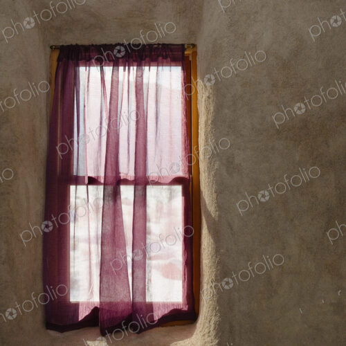 A small window in a wall, wooden frame, net curtain