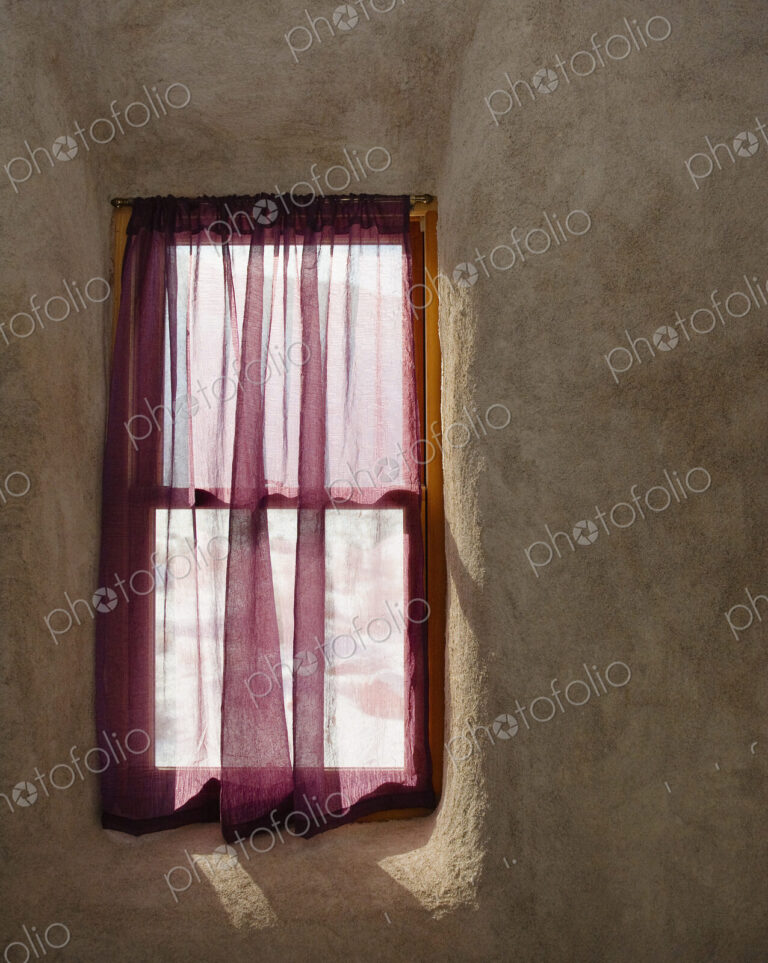 A small window in a wall, wooden frame, net curtain