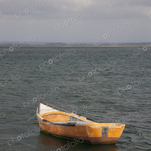 A small wooden boat moored in open water, off the Portuguese coast.
