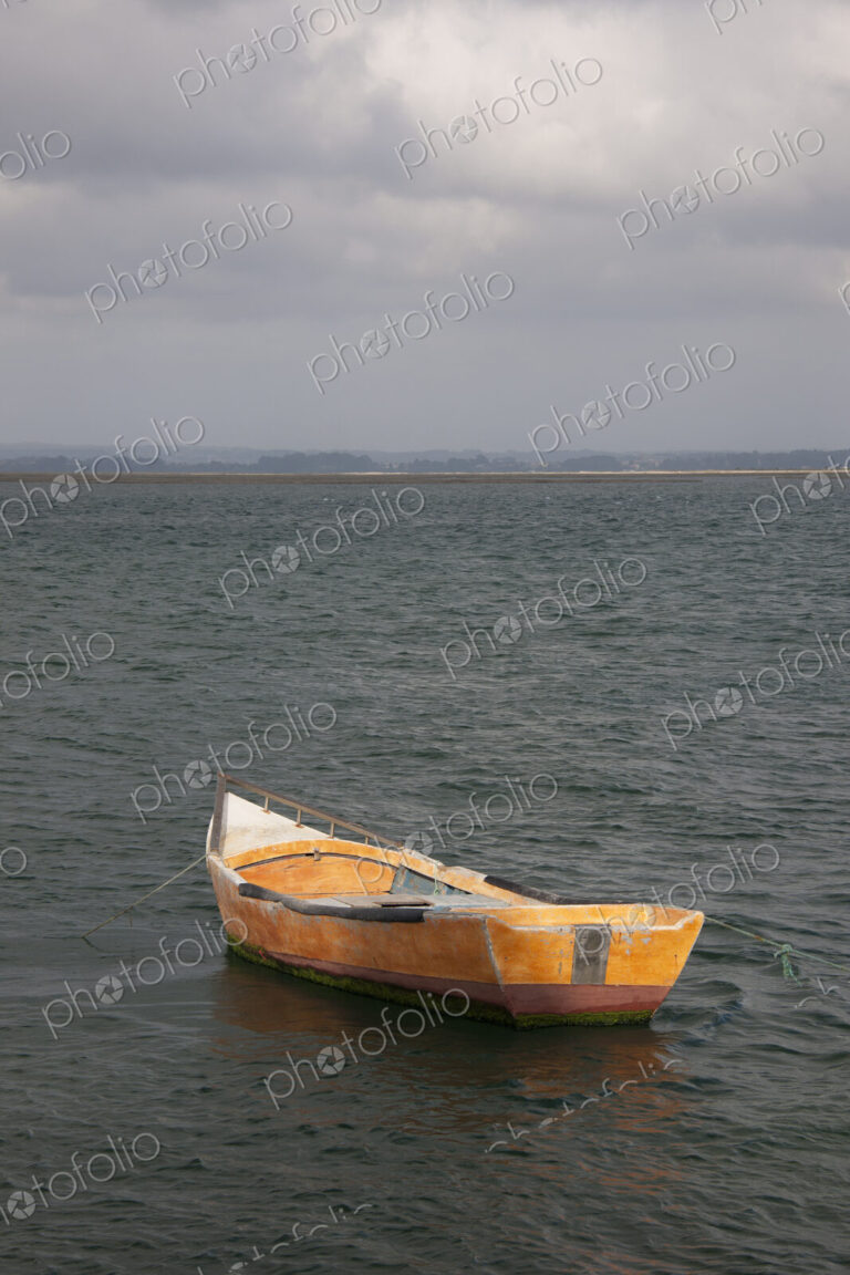 A small wooden boat moored in open water, off the Portuguese coast.