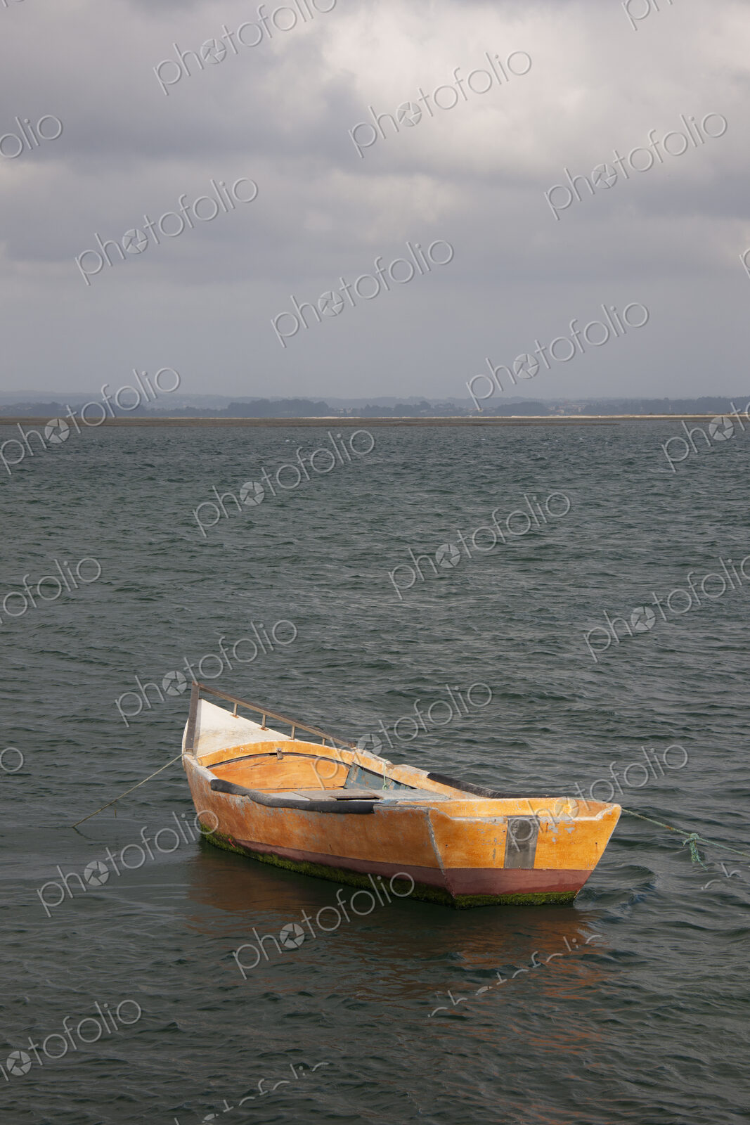 A small wooden boat moored in open water, off the Portuguese coast.