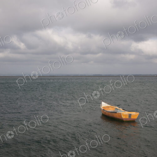 A small wooden boat moored in open water, off the Portuguese coast. A small wooden boat moored in open water, off the Portuguese coast.