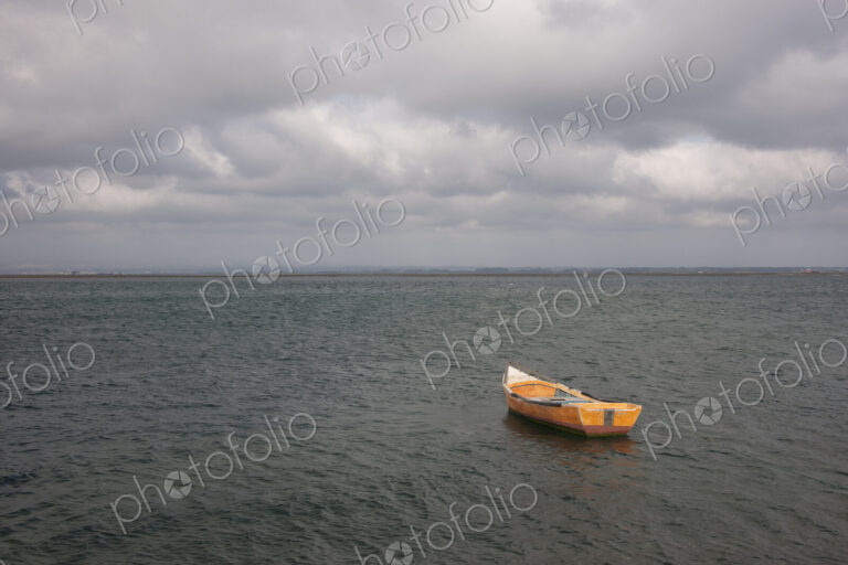 A small wooden boat moored in open water, off the Portuguese coast.