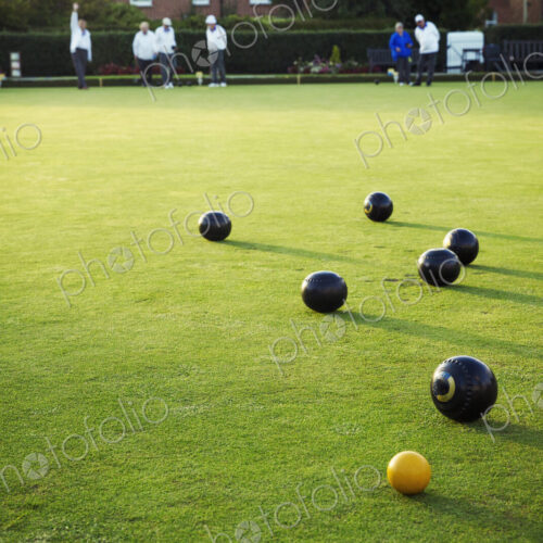 A small yellow target jack ball and a cluster of lawn bowls around it. A small yellow target jack ball and a cluster of lawn bowls around it.