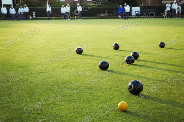 A small yellow target jack ball and a cluster of lawn bowls around it.