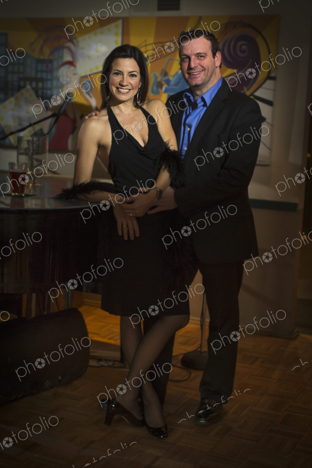 A smartly dressed man and woman side by side by a piano.