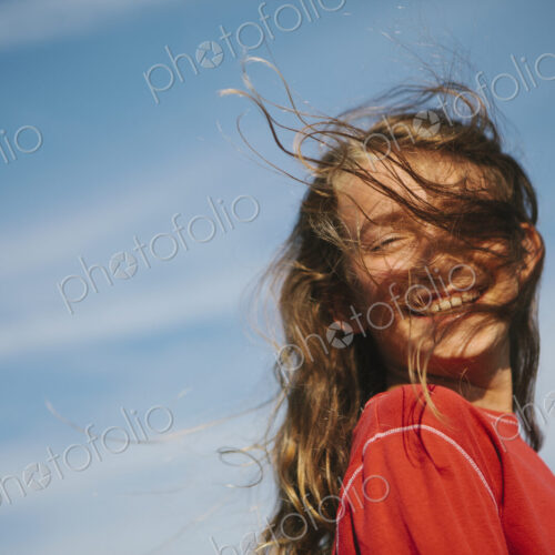 A smiling nine year old girl, with the wind blowing her hair over her face. A smiling nine year old girl, with the wind blowing her hair over her face.