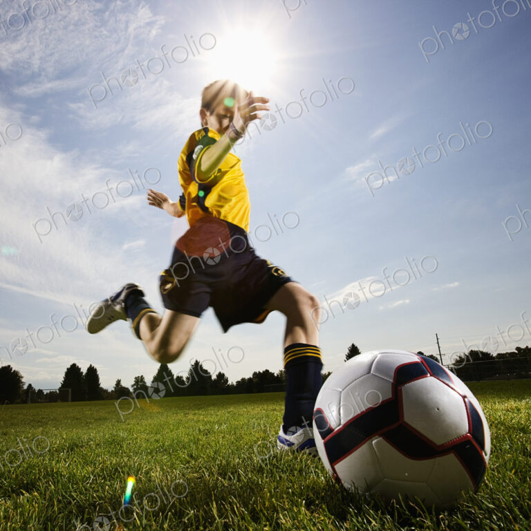 A soccer player, a boy preparing to kick a soccer ball.