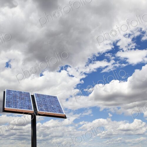 A solar panel stands against sky with clouds.