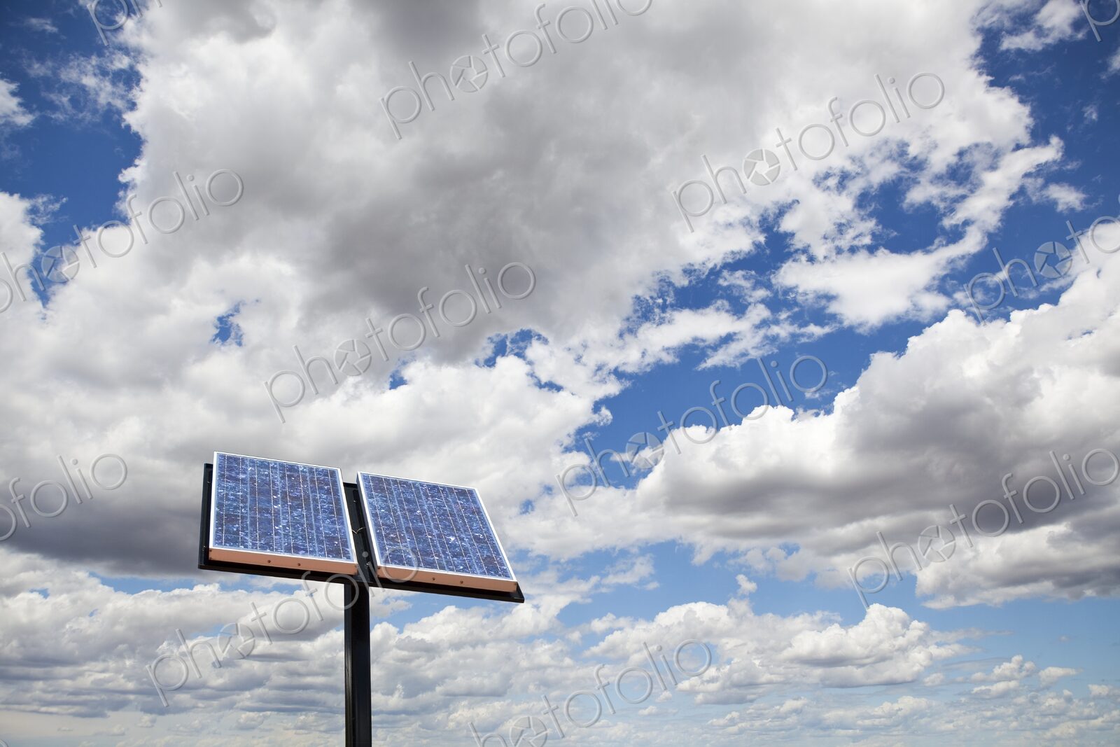 A solar panel stands against sky with clouds.