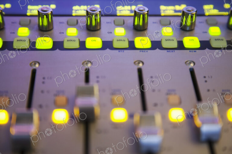 A sound board with lighted controls in a home recording studio