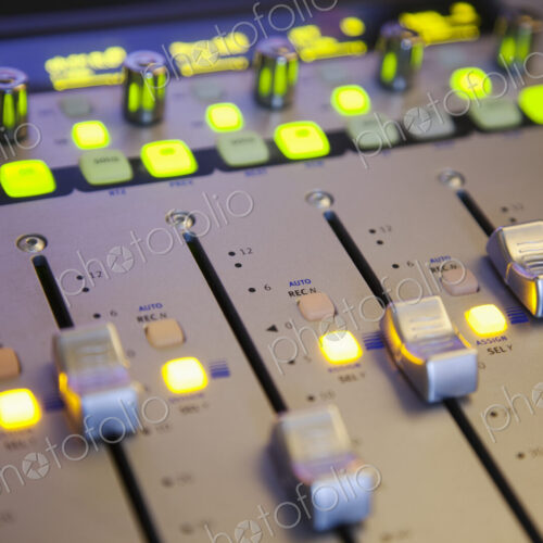 A sound board with lighted controls in a home recording studio A sound board with lighted controls in a home recording studio
