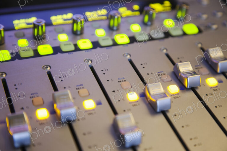 A sound board with lighted controls in a home recording studio