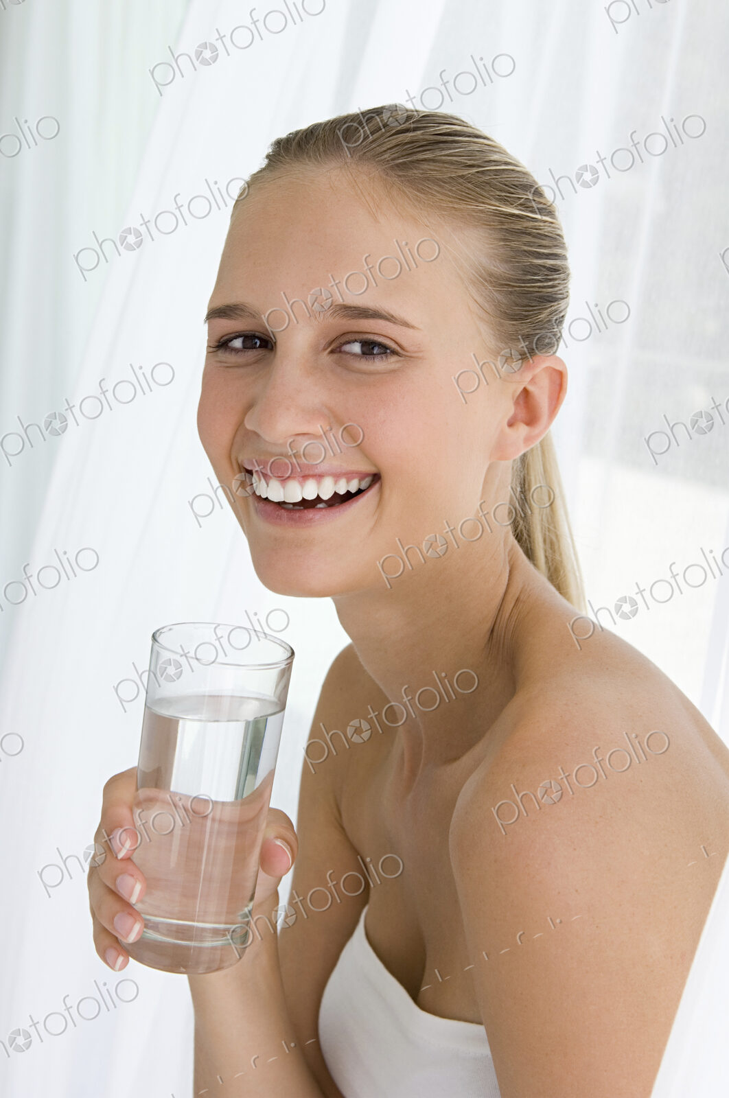 A spa treatment centre. A young woman drinking a glass of water.
