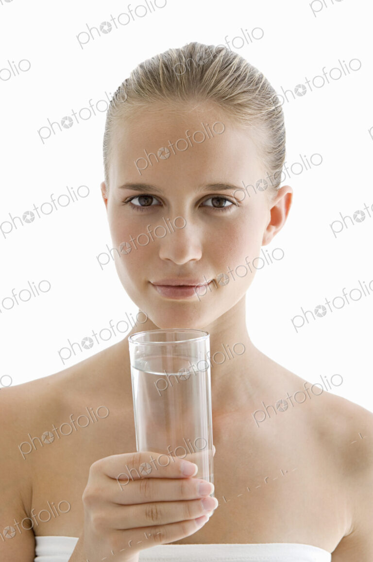 A spa treatment centre. A young woman drinking a glass of water for hydration.