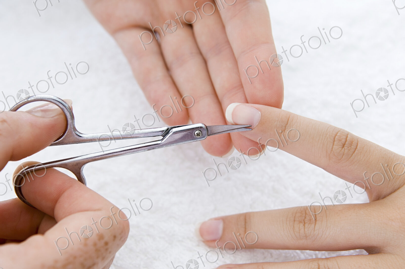 A spa treatment centre. A young woman having a manicure, having her fingernails shaped.