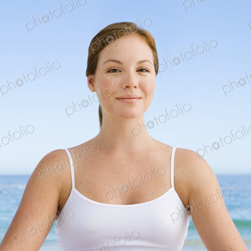 A spa treatment centre. A young woman seated in a relaxed pose on the beach.