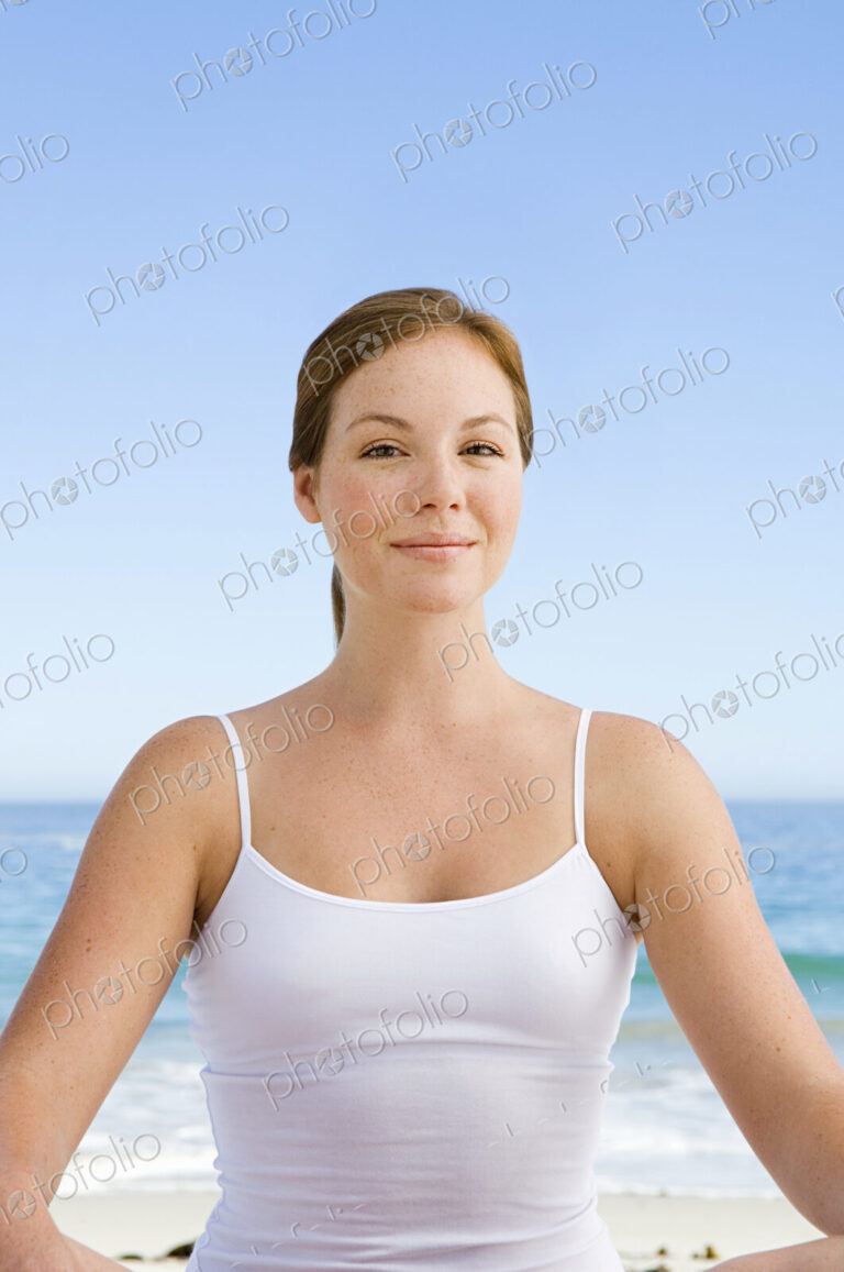 A spa treatment centre. A young woman seated in a relaxed pose on the beach.