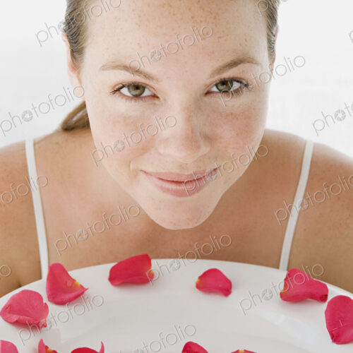 A spa treatment centre. A young woman with a white dish of pink rose petals. A spa treatment centre. A young woman with a white dish of pink rose petals.