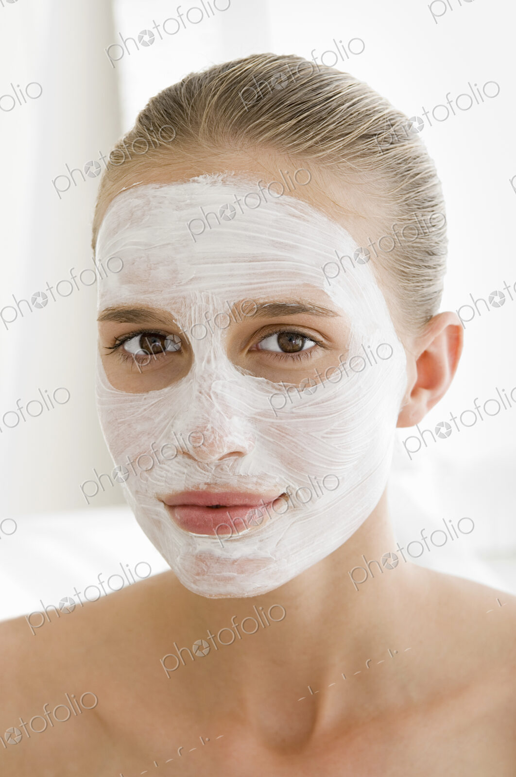 A spa treatment centre. A young woman with a white facial mask on her skin.