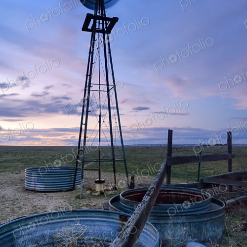A spinning windmill metal wheel and wind tower, blurred motion, at sunset on the… A spinning windmill metal wheel and wind tower, blurred motion, at sunset on the…