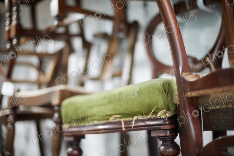A stack of antique chairs, with fraying seas for refurbishment.