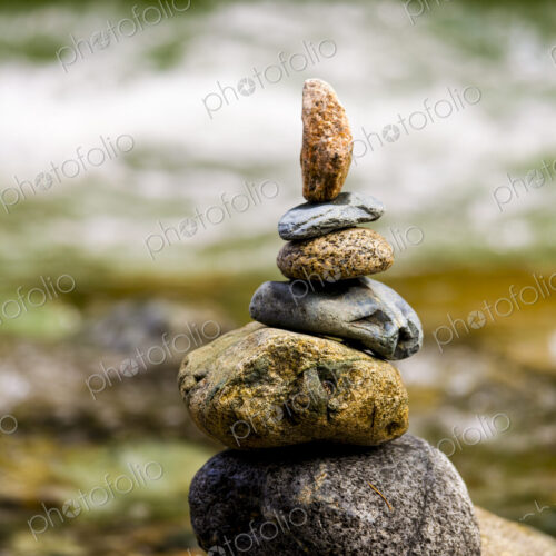 A stack of small rocks balanced on top of each other by a river. A stack of small rocks balanced on top of each other by a river.