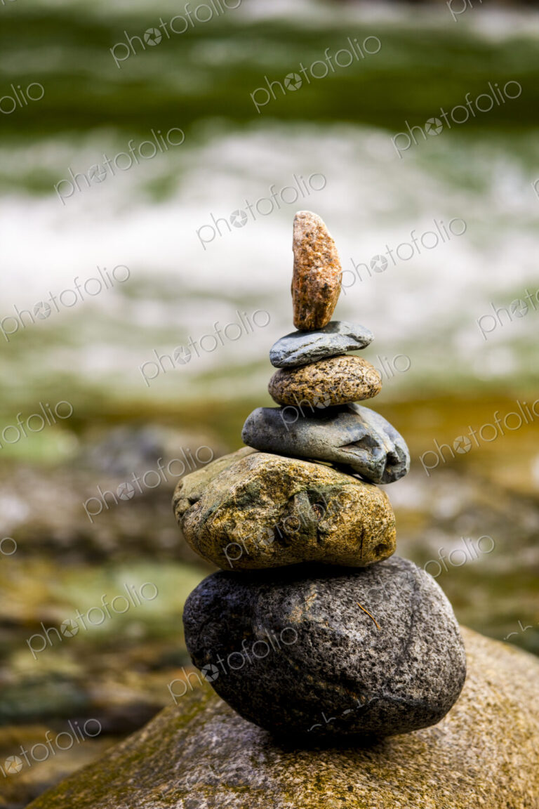 A stack of small rocks balanced on top of each other by a river.