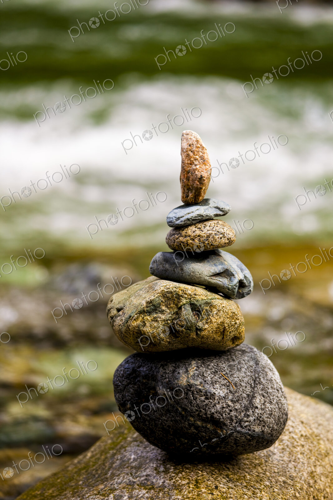 A stack of small rocks balanced on top of each other by a river.