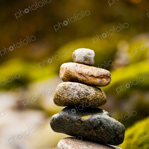 A stack of small rocks balanced on top of each other by a river. A stack of small rocks balanced on top of each other by a river.