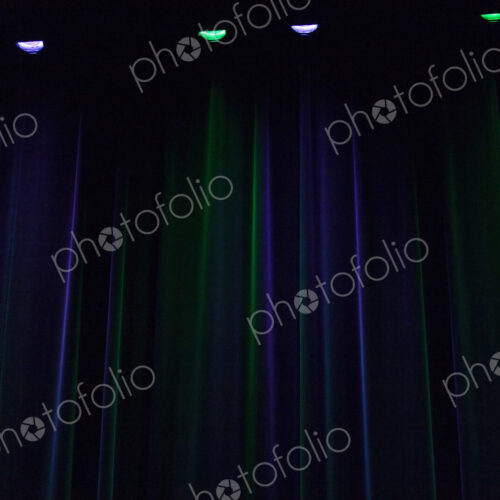A stage in darkness,curtains and points of light, downlighters green and purple colours. A stage in darkness,curtains and points of light, downlighters green and purple colours.