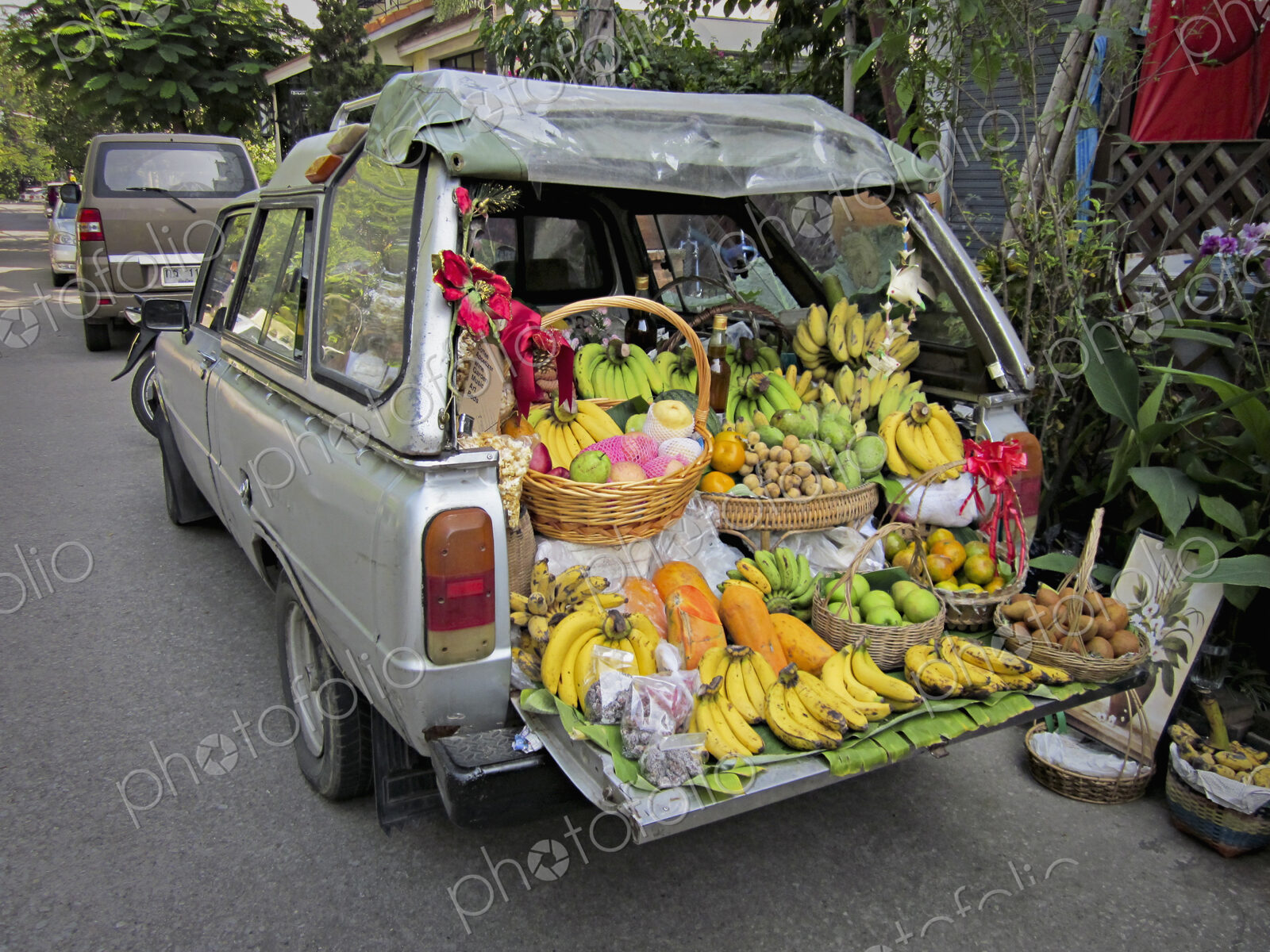A station wagon car with the tailgate down, loaded with produce for sale, fresh…