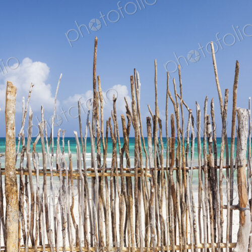 A stick fence along a white sand beach A stick fence along a white sand beach