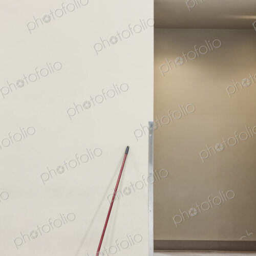 A still life view of a broom leaning up against a wall.