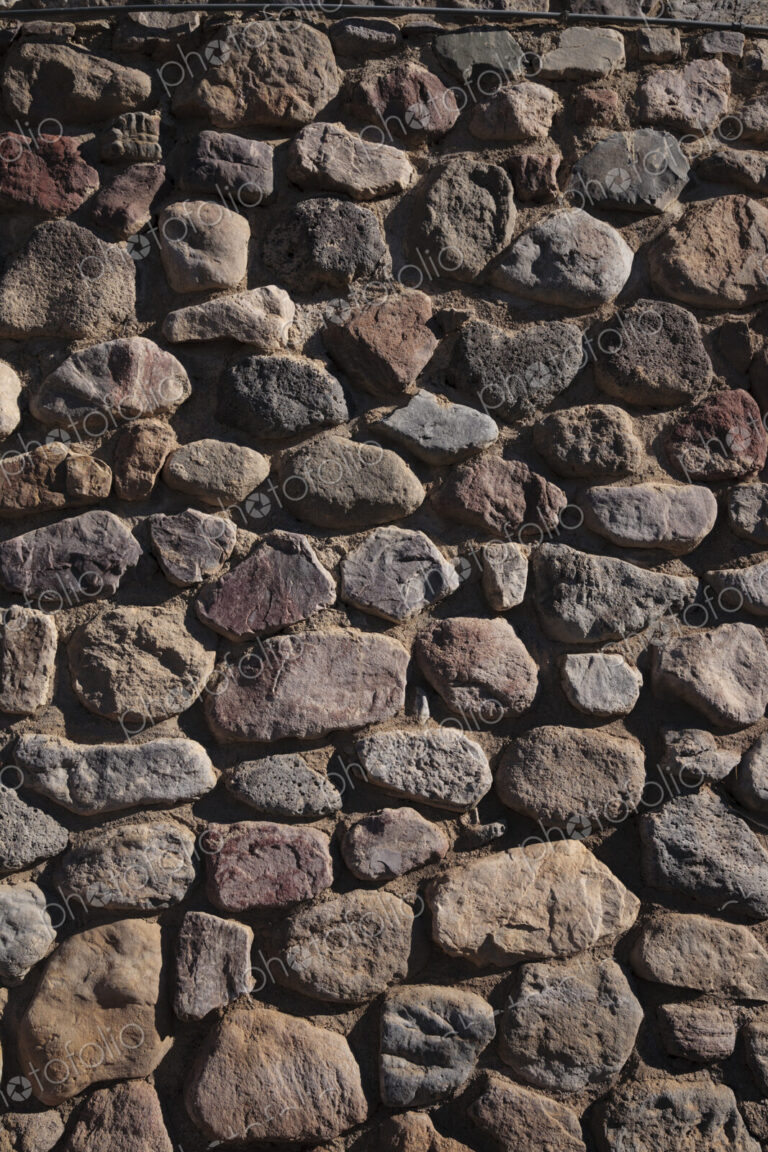 A stone wall with irregular shaped stone blocks fitted together.